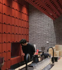 A bustling cafe with a brick wall, red tile backsplash, and various cups and bottles scattered around the room