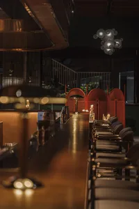 Inviting bar area with a wooden counter, red-accented chairs, and potted plants, creating a comfortable dining experience