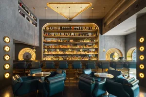 A sophisticated bar area with a liquor display behind the counter, surrounded by chairs and an elegant atmosphere