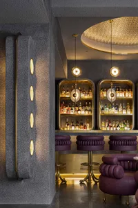 Modern bar area with purple countertop, bottles, and seating, set in a stylish and inviting environment