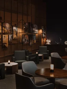 Cozy restaurant interior with wooden walls, tables, and chairs, featuring soft candlelight and a modern design