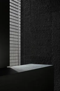 Dark interior space with a stone wall featuring two windows, one on each side, and a lack of natural light