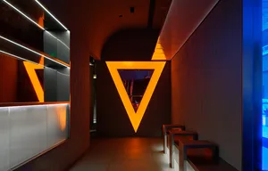 Dimly lit room with a large triangle shape, chairs placed around the space, and a contemporary feel
