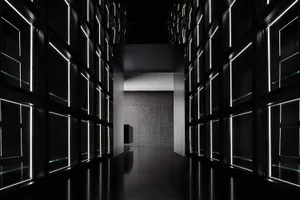 A calm and quiet black and white hallway with lights on the walls, inviting exploration