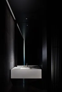 Modern bathroom with a white marble sink, black wall, and two bottles near the sink