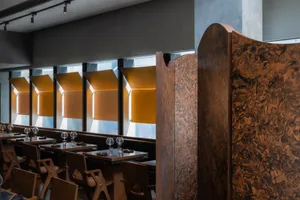 Empty restaurant interior with wooden walls and tables, featuring chairs and wine glasses, in a calm and inviting atmosphere