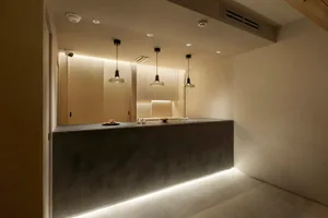 Empty kitchen with a gray countertop, white walls, and overhead lighting, featuring a sink and modern cabinets
