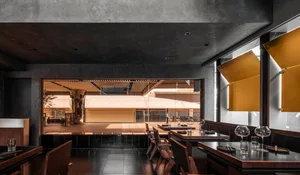 Elegant dining space with wooden tables, multiple chairs, and various table settings, illuminated by natural light