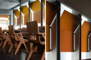 A modern restaurant dining area with wooden chairs and tables, dimly lit for a cozy ambiance