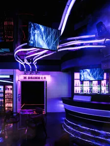 A stylish bar area with purple lighting, multiple TV screens, and comfortable seating for patrons