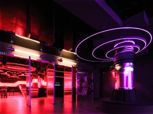 A modern gallery with a circular central structure, surrounded by red walls and glass doors, creating a vibrant atmosphere