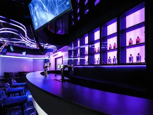 A cozy bar area with a wooden counter, chairs, and bottles, creating a relaxed atmosphere