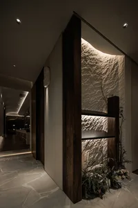 A warm and inviting room with a wooden doorway, stone wall, chairs, and a potted plant, conveying a residential or commercial setting