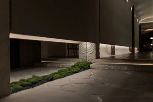 A calm indoor space with a stone wall, a small green plant, and two chairs, creating a serene atmosphere