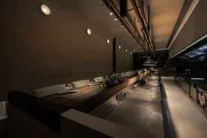 Dimly lit restaurant with wooden floors and tables, featuring chairs and a cozy atmosphere