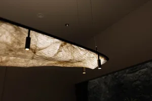 A cozy room with a unique spider web-shaped lamp, natural light, and a wall and window