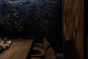 A dining area with a wooden table and leather chairs in a well-lit space, possibly with natural light from windows