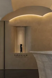 A modern art gallery with a black sculpture on a pedestal surrounded by artwork-adorned walls