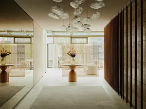 Modern living area with two couches, three chairs, artwork on the walls, and natural light from windows
