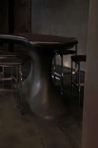 A modern dining space with a large wooden table surrounded by four black chairs in a stylish environment