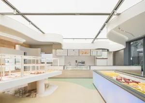 A modern restaurant kitchen and dining area with a large counter, dining table, and comfortable seating for guests