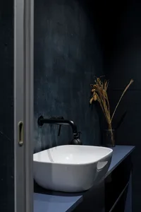 A clean and organized bathroom with a white sink on a countertop, surrounded by vases and a well-organized space