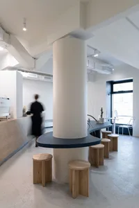 Modern restaurant interior with a central pillar, dining tables, and chairs, giving off a stylish and modern vibe