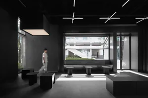 Empty black and white room with a large window, tables, and chairs in a modern minimalist space