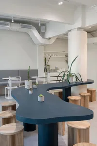 A cozy cafe with a large dining table surrounded by chairs, potted plants, and decorative items, creating a warm and inviting atmosphere