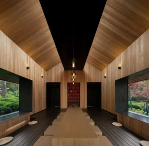 Open living area with wooden floors and walls, featuring two dining tables, chairs, and decorative books, with a warm and inviting atmosphere