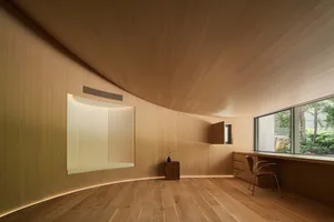 Open living area with hardwood floors, wooden walls, a potted plant, and decorative vase