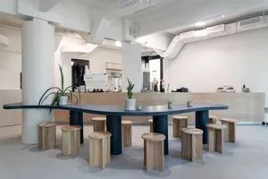 溫暖舒適的開放式廚房區域，配有大型餐桌、盆栽植物和咖啡機，周圍環繞舒適座椅與自然光線