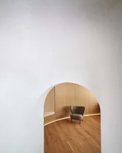 A minimalist interior design featuring a white room with wooden floors and a wooden chair, emphasizing simplicity and functionality