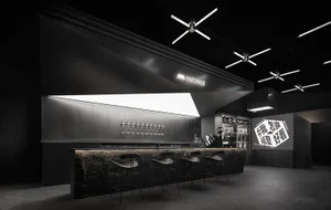 A cozy bar area with a wooden counter, chairs, and bottles on display, creating a welcoming atmosphere for patrons