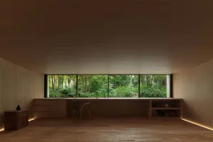 Open living area with a large window, two chairs, a dining table, and a potted plant, bathed in natural light