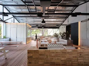 A restaurant with a large dining table, potted plants, and comfortable seating for guests