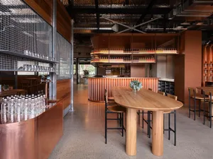 A wooden table and chairs in a bar area with bottles on the countertops, creating an inviting atmosphere for socializing and enjoying drinks