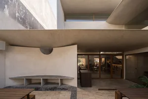 Open modern restaurant with concrete walls, wooden tables, and pendant lighting