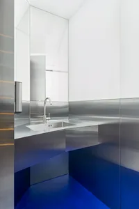 Industrial bathroom with a metal sink and mirror, featuring a silver-framed mirror and a well-lit atmosphere