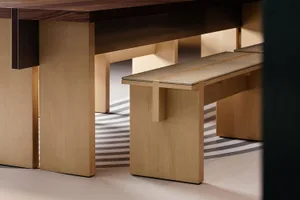 A wooden dining table with a bench on one side, set in a rustic dining space with a brown table surface and wooden bench