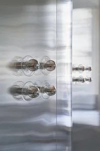 Modern bathroom with a chrome mirror and three clear glass cups on a countertop