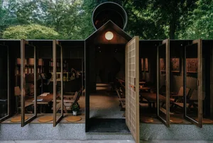 Open restaurant interior with wooden tables and chairs, wood flooring, and warm atmosphere