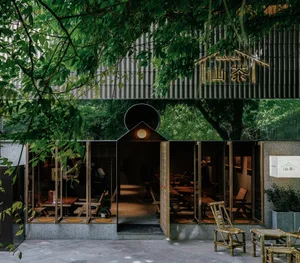Modern Asian restaurant with a large dining area, chairs, and benches, surrounded by natural elements and well-lit interior