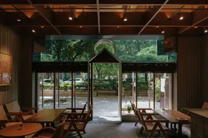 Modern restaurant interior with wooden floors and walls, featuring multiple chairs and a comfortable dining area