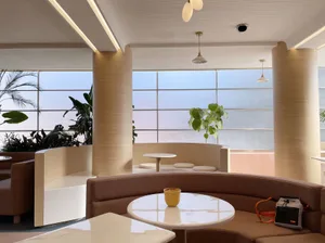 A restaurant dining area with a large table surrounded by chairs, potted plants, and inviting atmosphere
