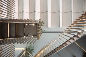 A modern staircase with wooden steps and a metal railing, featuring a potted plant at the base, set within a functional interior design space