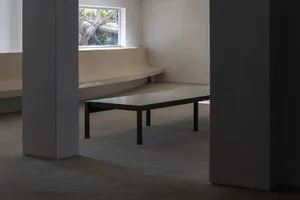Empty living area with a bench in front of a large window, allowing sunlight to enter