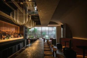 A cozy bar area with a wooden counter and chairs, featuring bottles on display and a relaxed atmosphere