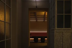 Cozy room with a red bench and three chairs, surrounded by white walls and dim lighting