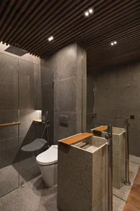 Bathroom with a white toilet, stone sink, and wooden bench, featuring a modern and minimalist design